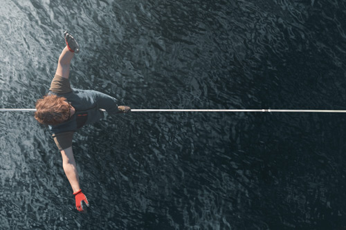 A man balances on a tightrope over water