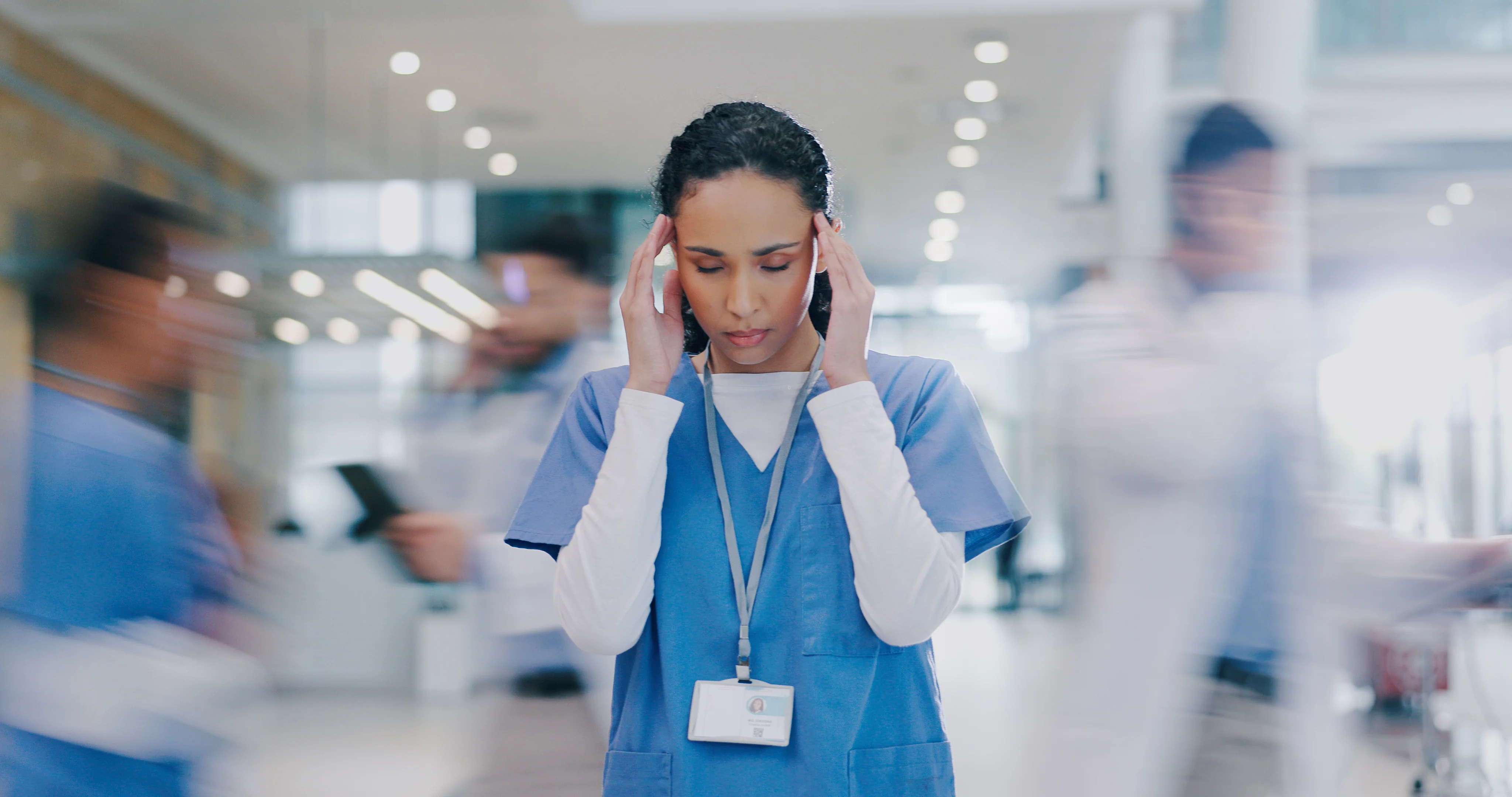 Ärztin, die sich im geschäftigen Krankenhaus den Kopf hält_Online-Fortbildung_Stark im Stress