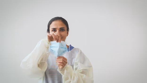Woman pulling medical face mask vertically to open pleats