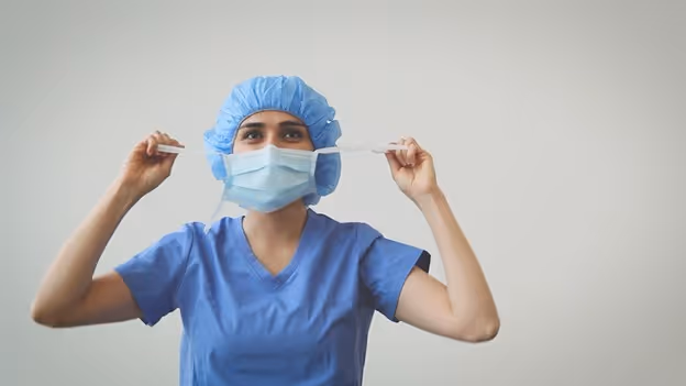 medical professional using upper ties of PRIMED surgical tie face mask to pull the mask away from their face
