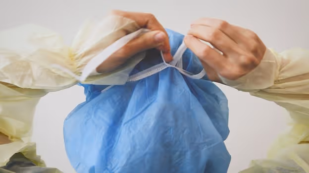 medical professional ties upper tie on a PRIMED surgical tie face mask across the crown of their head