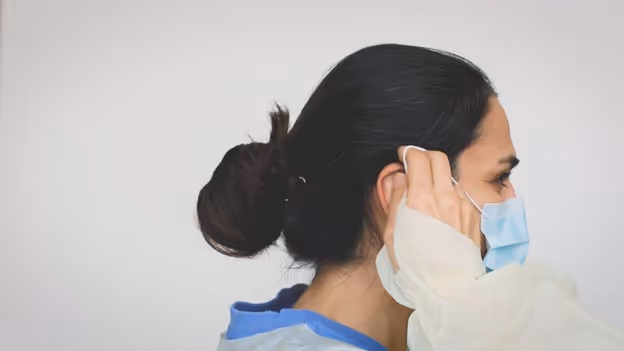 Woman securing medical face mask behind ears with loops