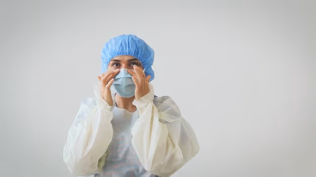 medical professional secures fit of a PRIMED surgical tie face mask by pressing against the bridge of their nose and cheeks after tying
