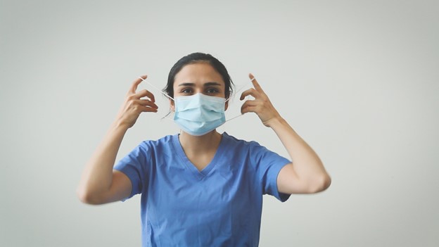 woman removing medical face mask by the loops