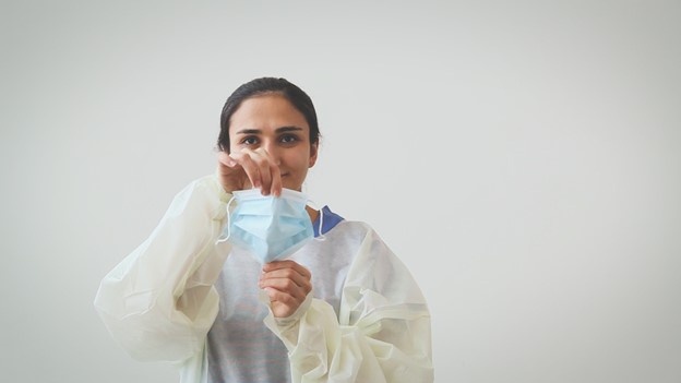 Woman pulling medical face mask vertically to open pleats