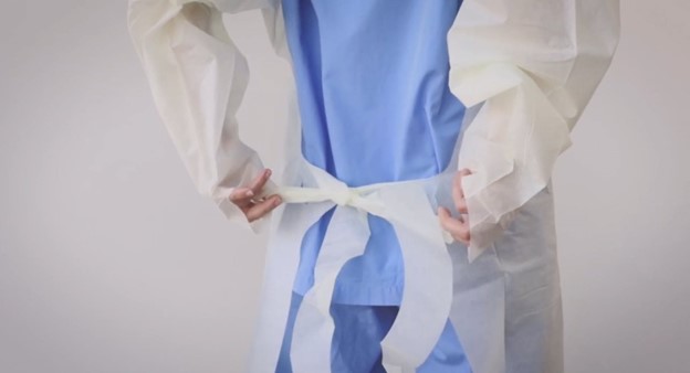 Donning single-use overhead open back thumbloop gown with waist tie