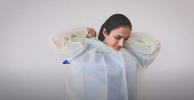 Donning single-use overhead open back thumbloop gown