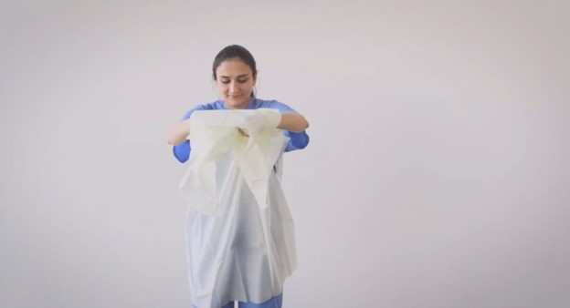 Pulling waist of gown to break tie to doff gown