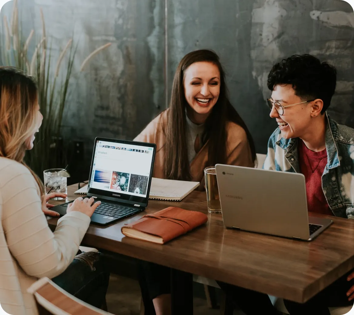 a group of women sitting at a table with laptops