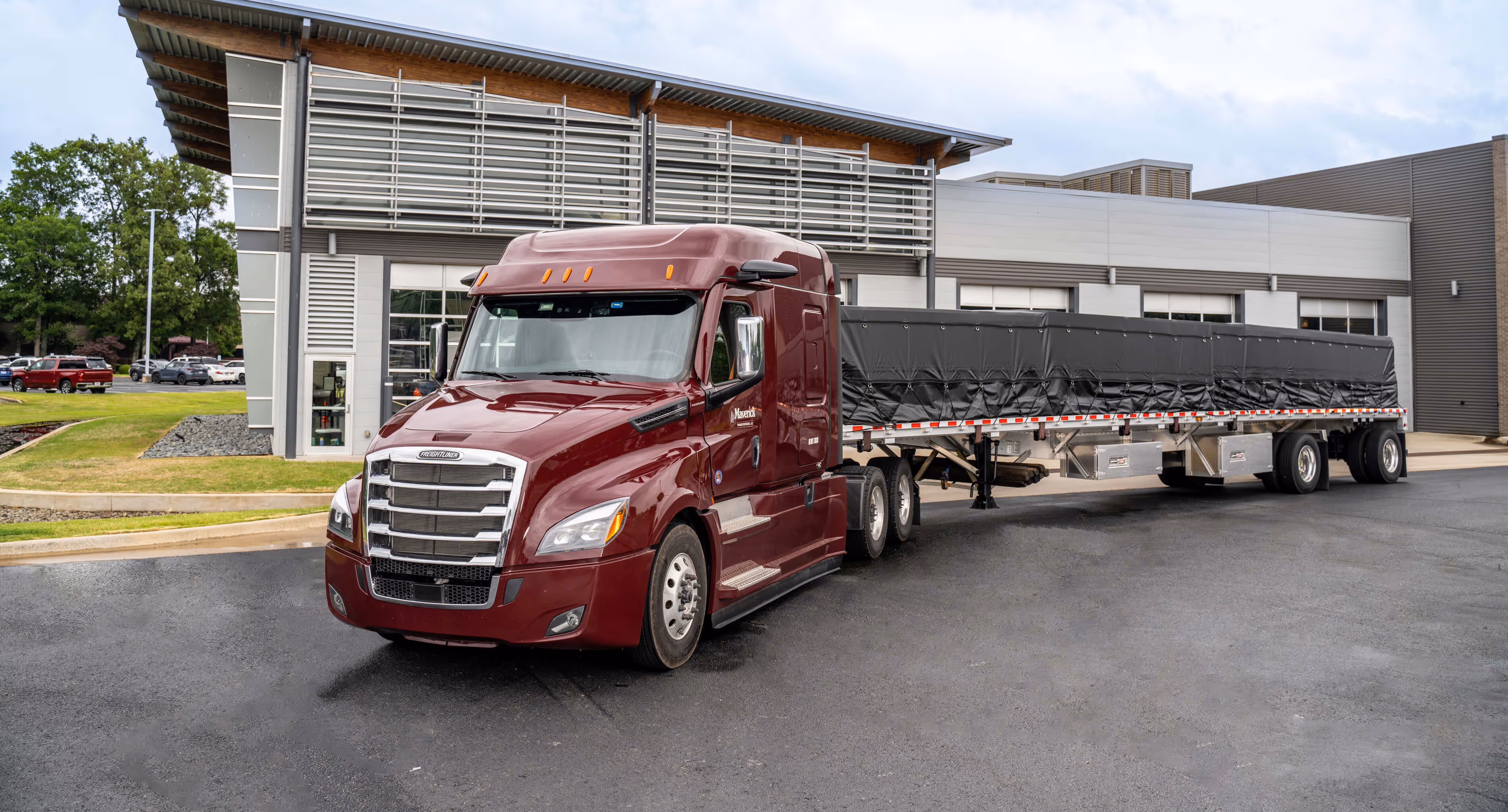A red semi truck parked in front of a building.