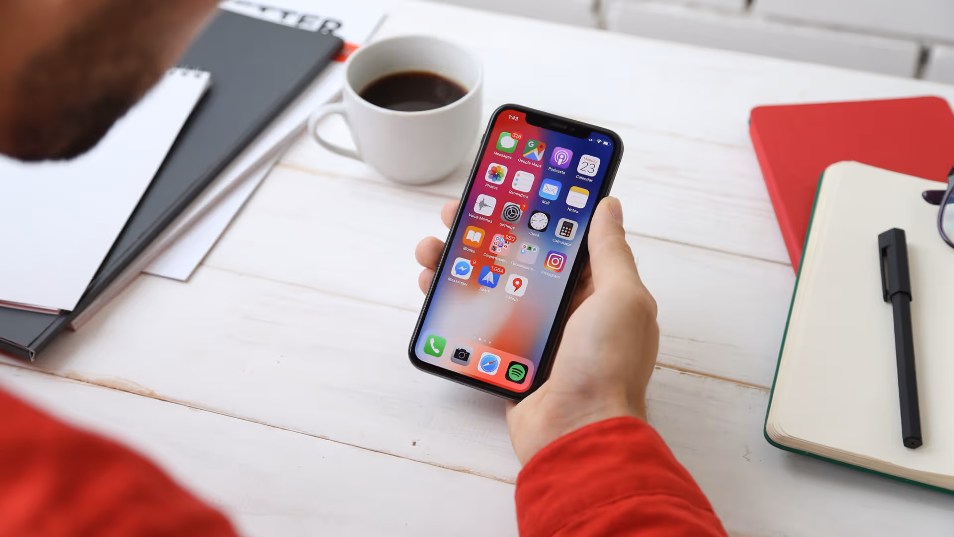 Hand holding mobile phone displaying home screen of iPhone apps