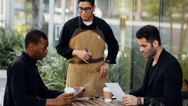 Two people at a restaurant table about to order with the server