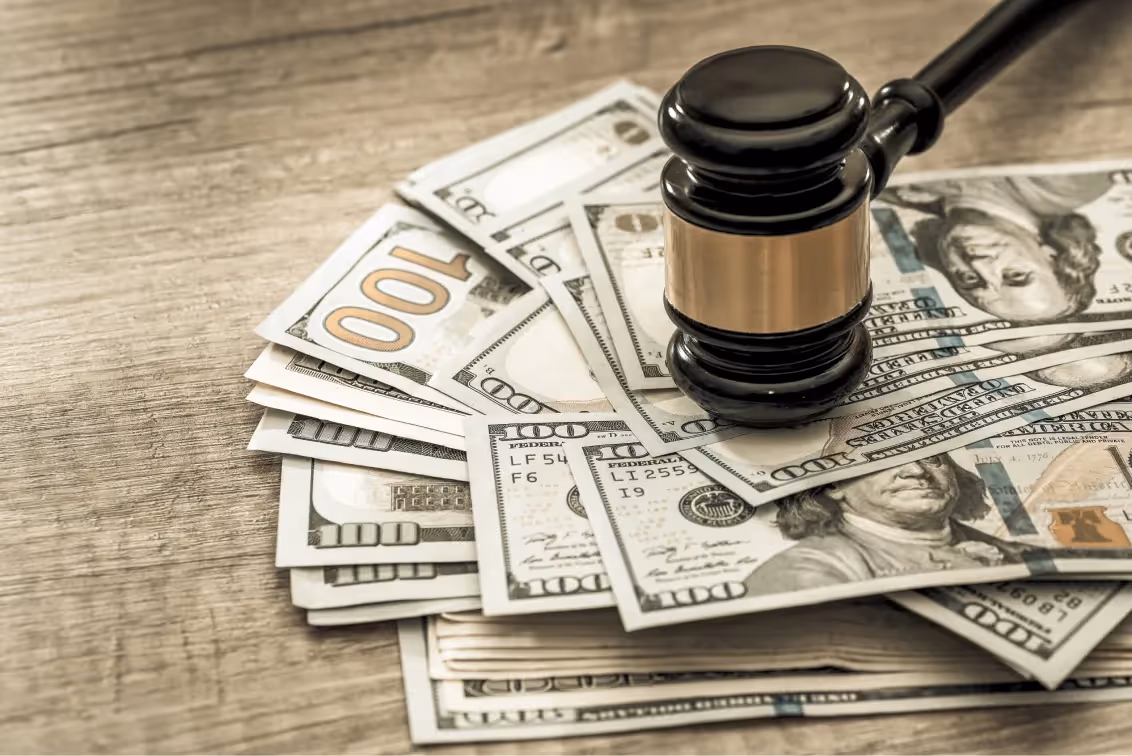 Gavel resting on dollar bills for a sexual assault settlement