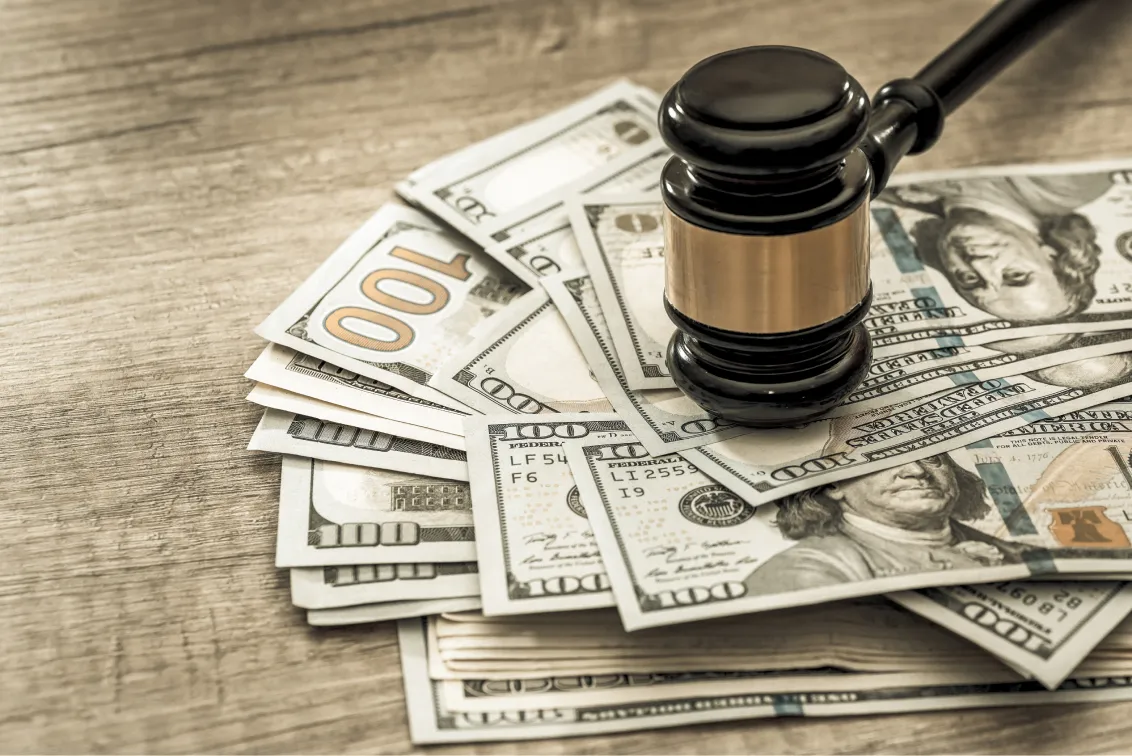 Gavel resting on dollar bills for a sexual assault settlement