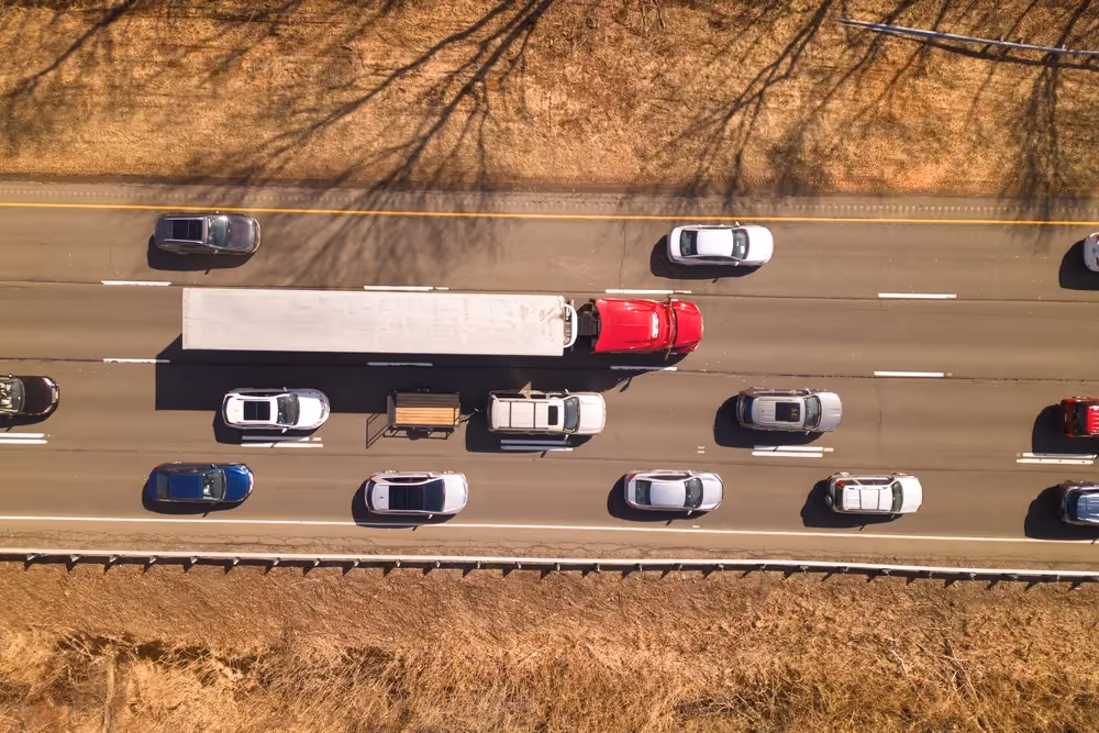 Aerial view of a busy highway with a white truck among surrounding cars