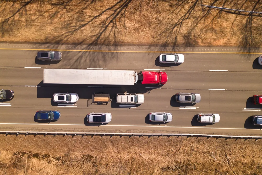 Aerial view of a busy highway with a white truck among surrounding cars