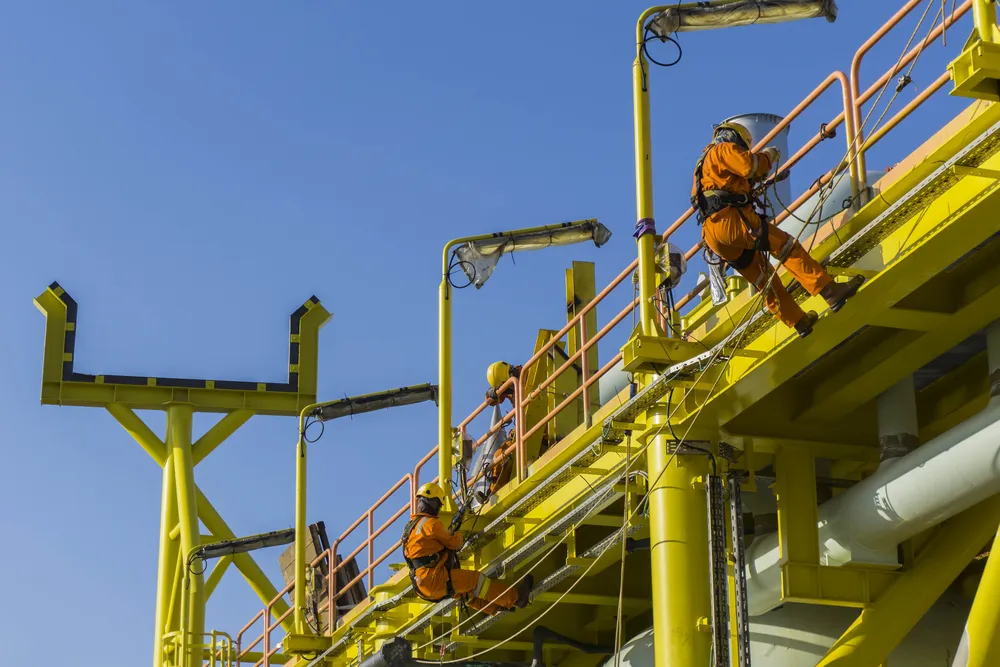 Construction workers suspended from a railing at an industrial work site