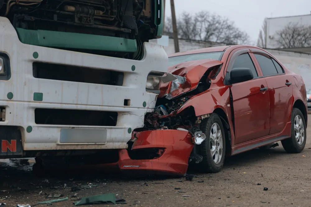 Red car involved in a truck accident with a white semi truck