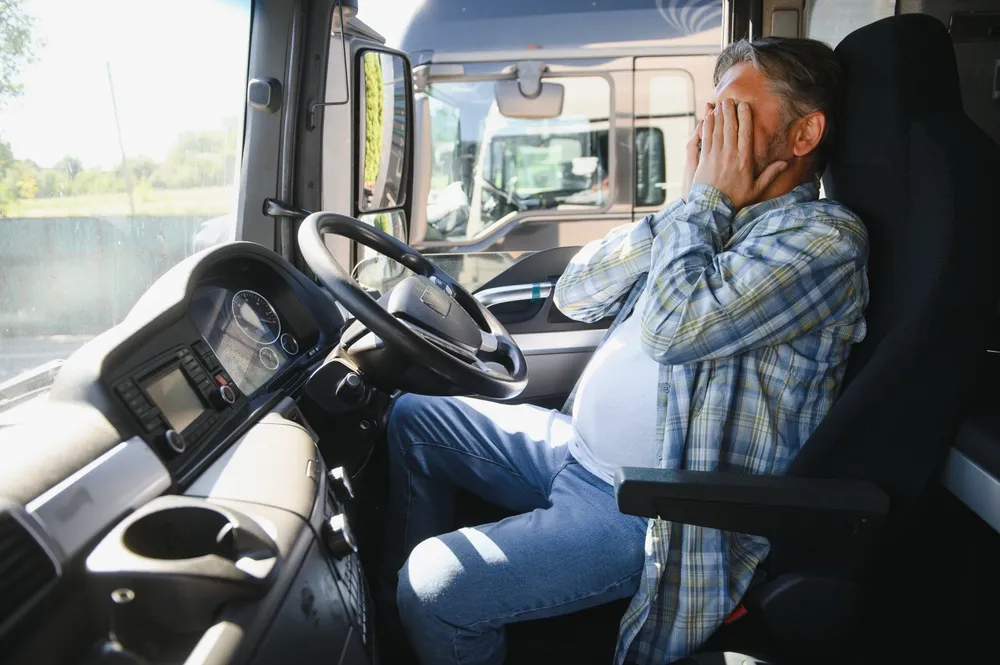 Truck driver covering his face while sitting inside a commercial truck