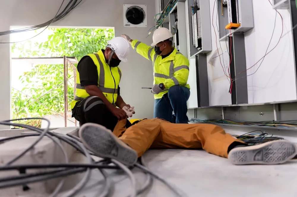 Workers helping an injured electrician after an electrical shock accident