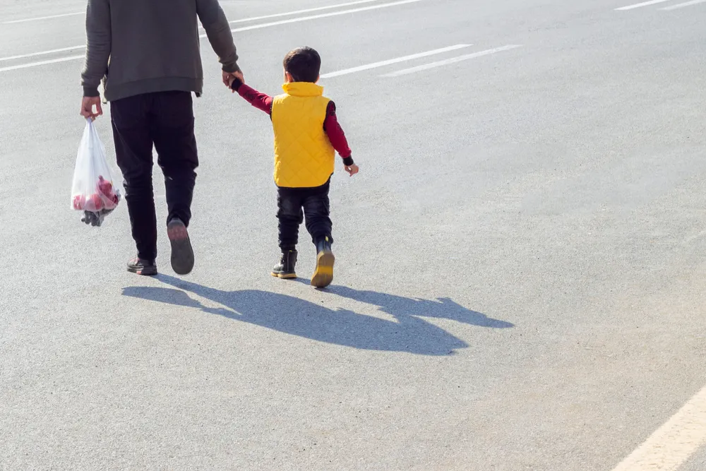 Father and child crossing a California street outside a crosswalk