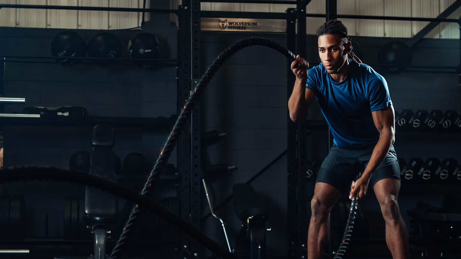 A man in a gym using battle ropes