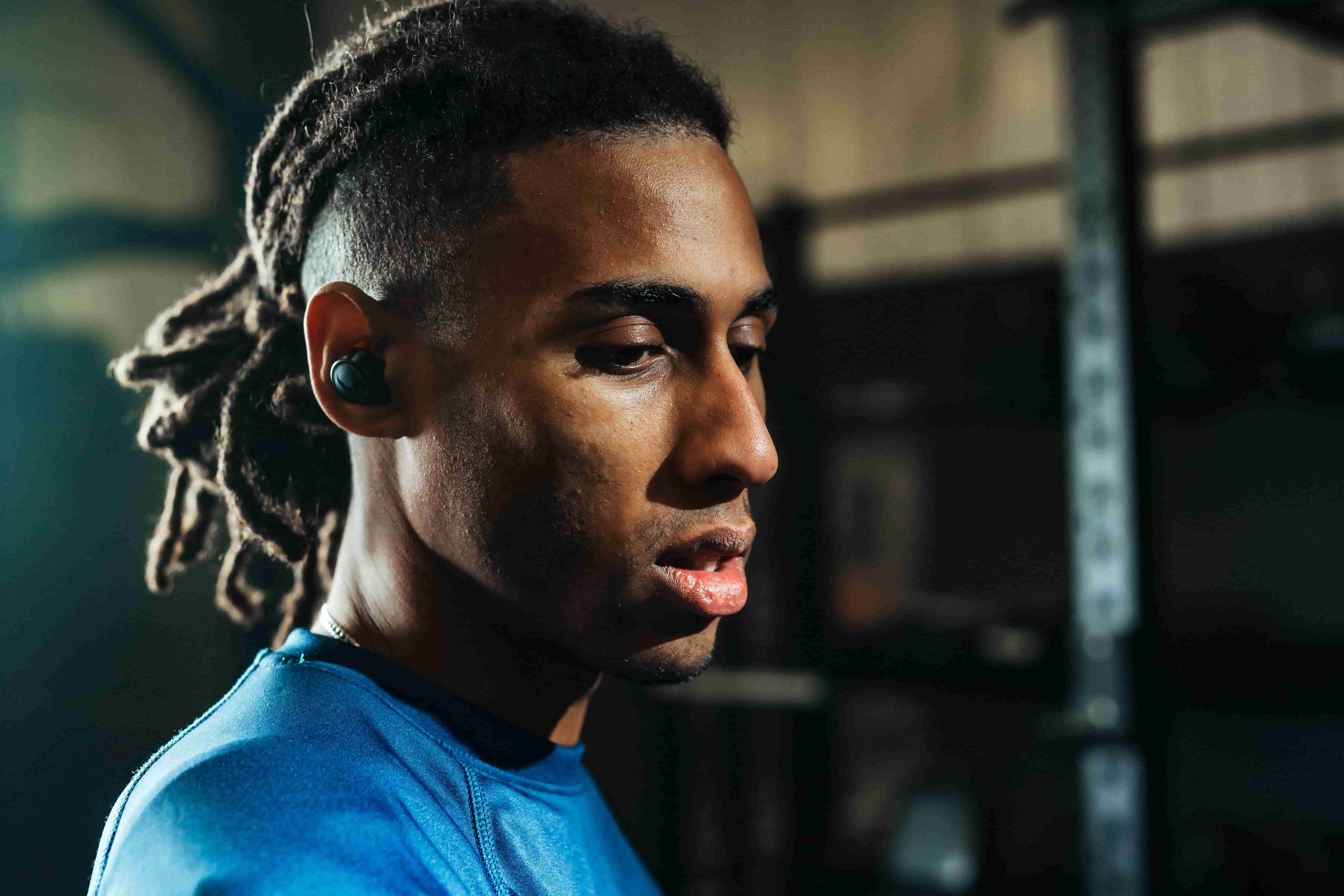 Young Black male athlete wearing best earbuds for running during gym workout session