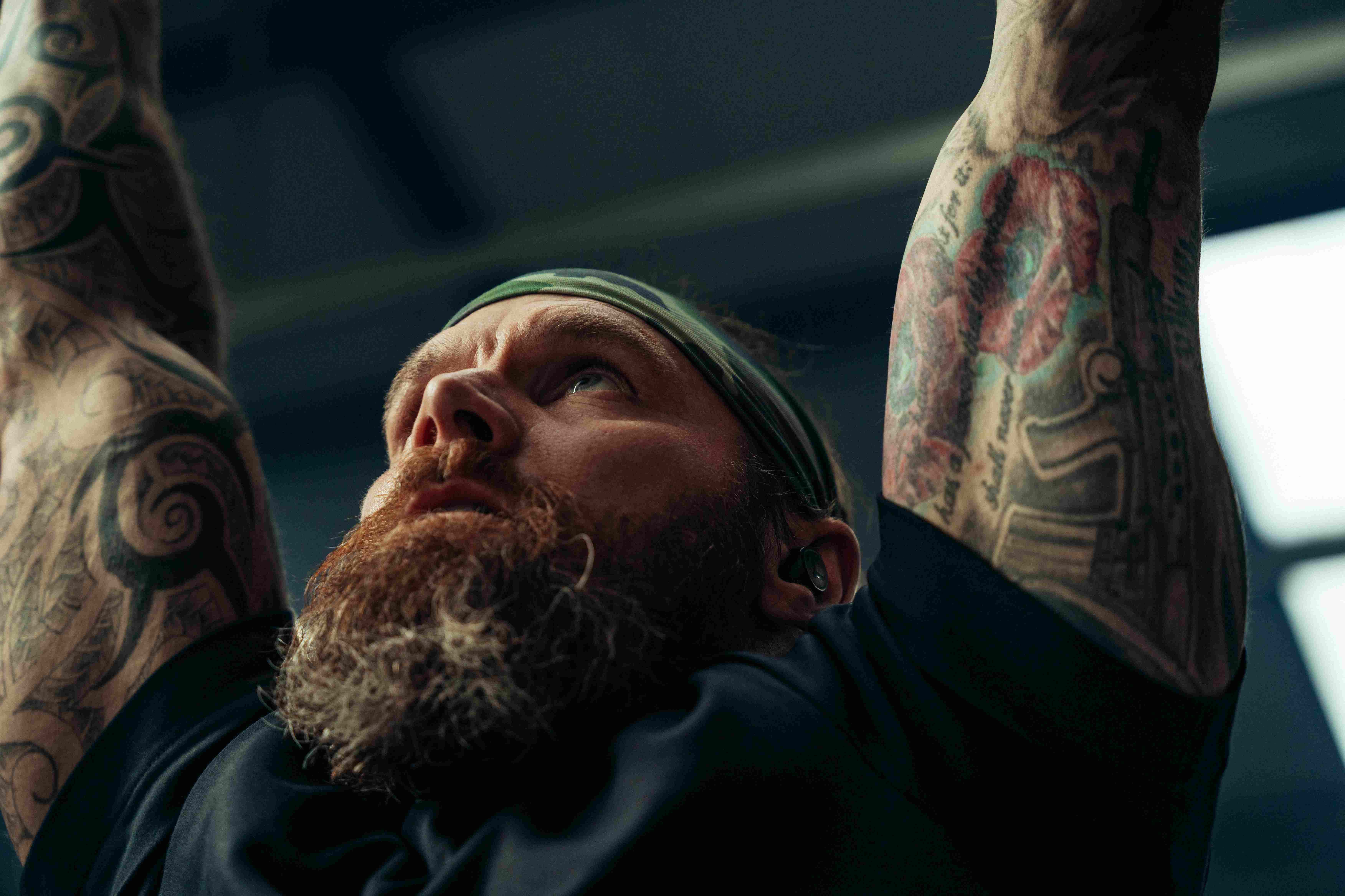 Athlete mid-pull-up with phone-free workout earbuds — full focus, no distractions