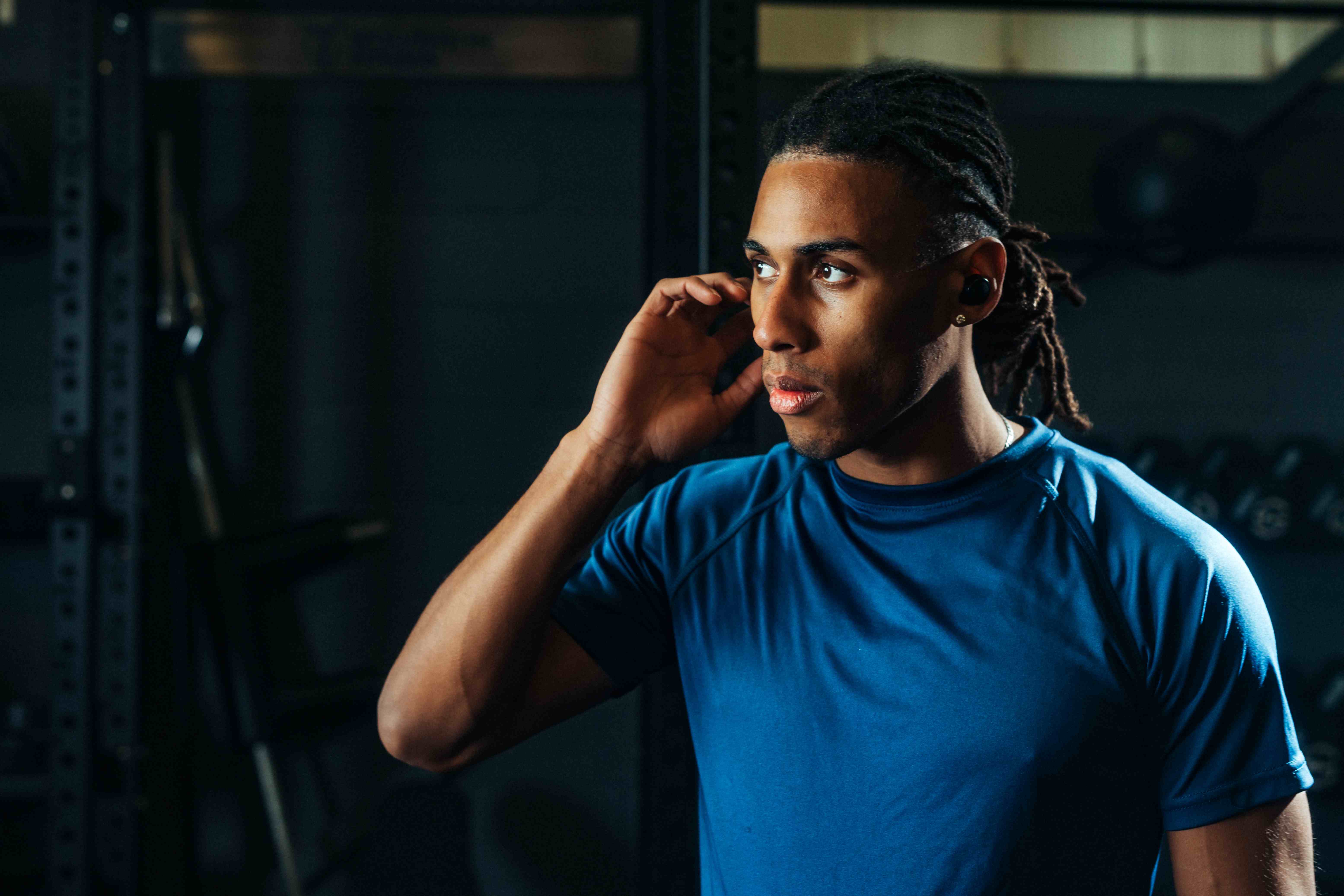 Athlete tapping earbud to change gym music without a phone — earbuds vs smartwatch for gym music