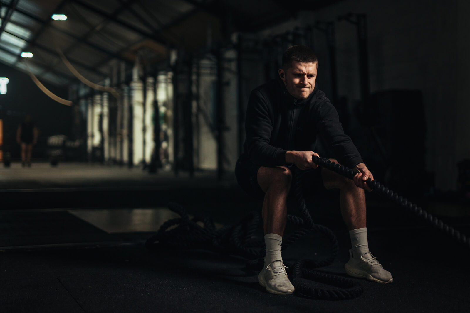 Athlete pulling a sled wearing black Tzuka TZ7 Ultra in-ear earbuds