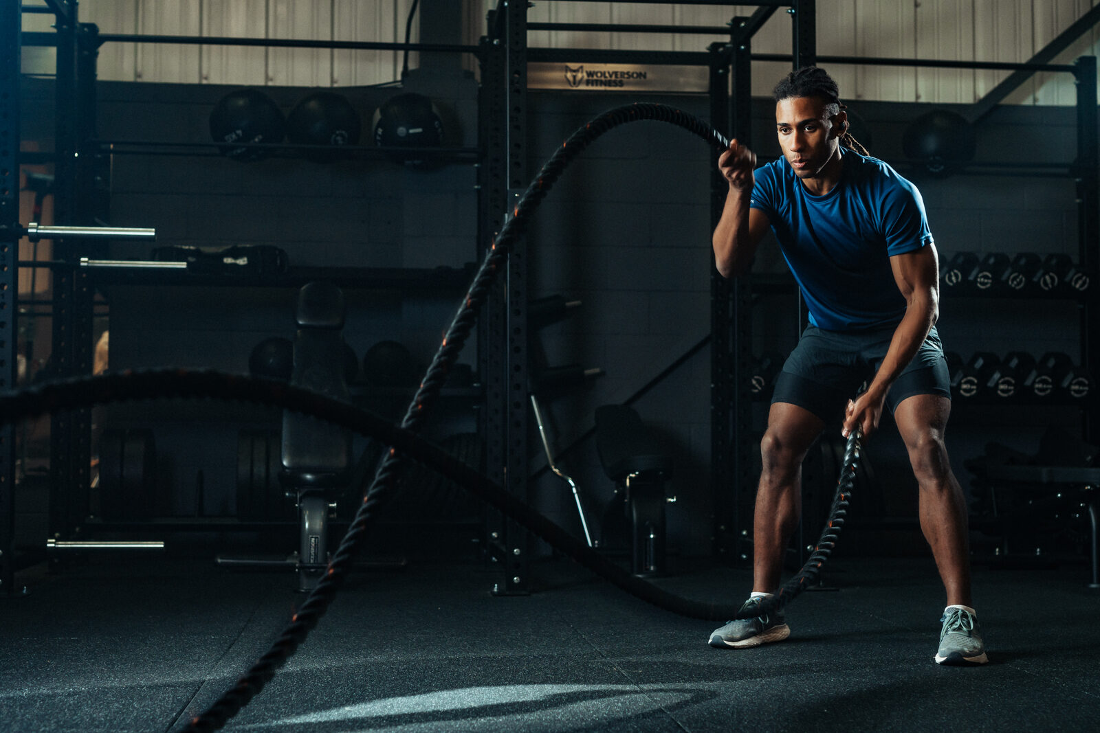 Athlete on battle ropes mid-interval wearing black Tzuka earbuds