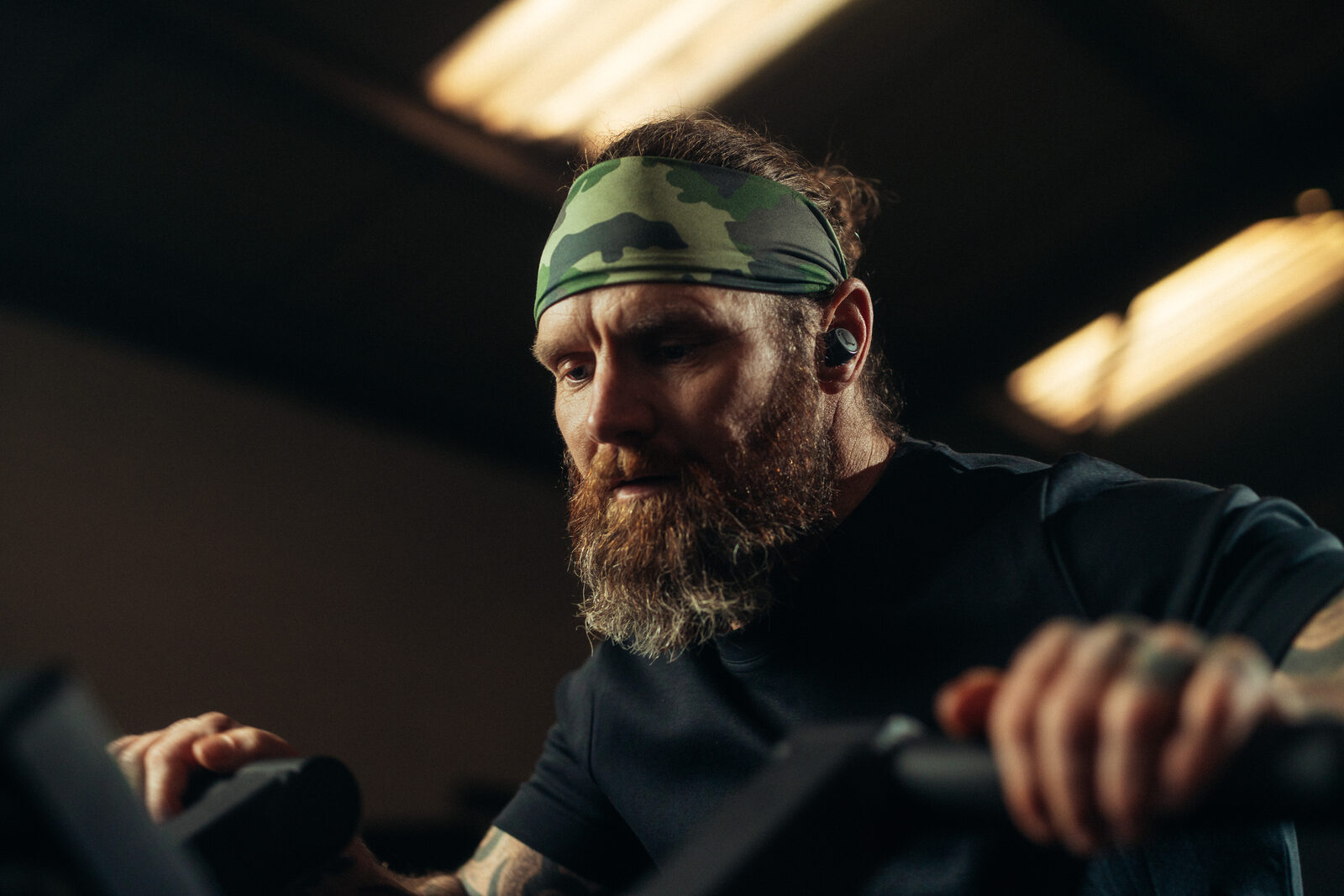 Athlete working on the echo bike under fatigue wearing Tzuka TZ7 Ultra earbuds