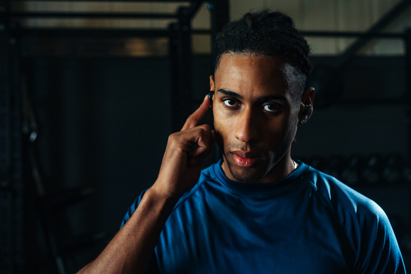 Athlete tapping the touch control on a Tzuka earbud, no phone required