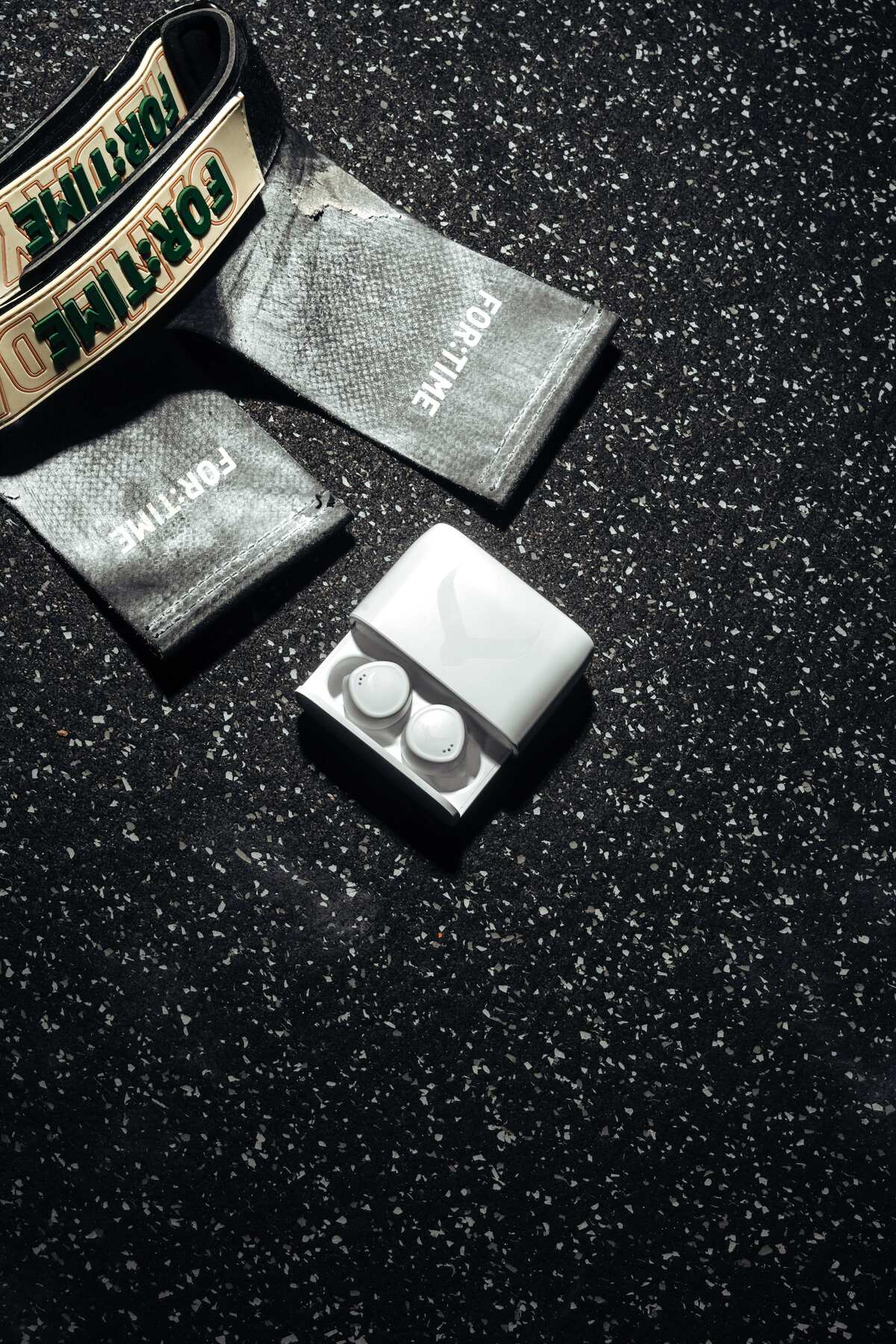 White Tzuka earbuds and charging case laid out with training grips