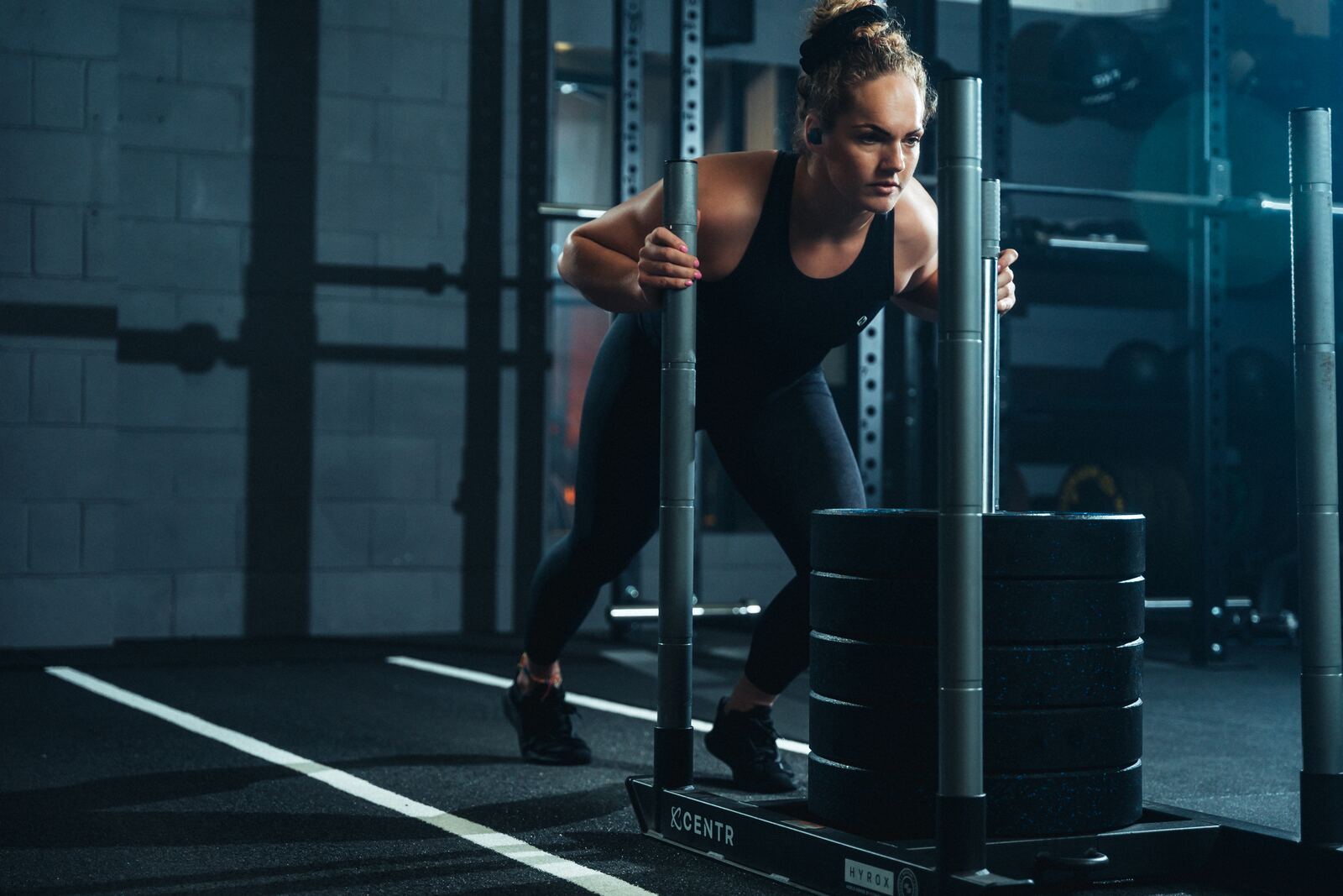 Athlete driving a heavy sled push during HYROX training