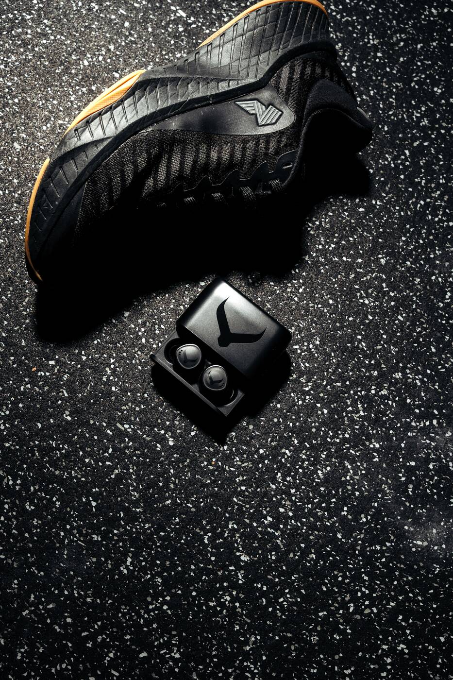 Tzuka TZ7 Ultra earbuds and charging case beside training shoes
