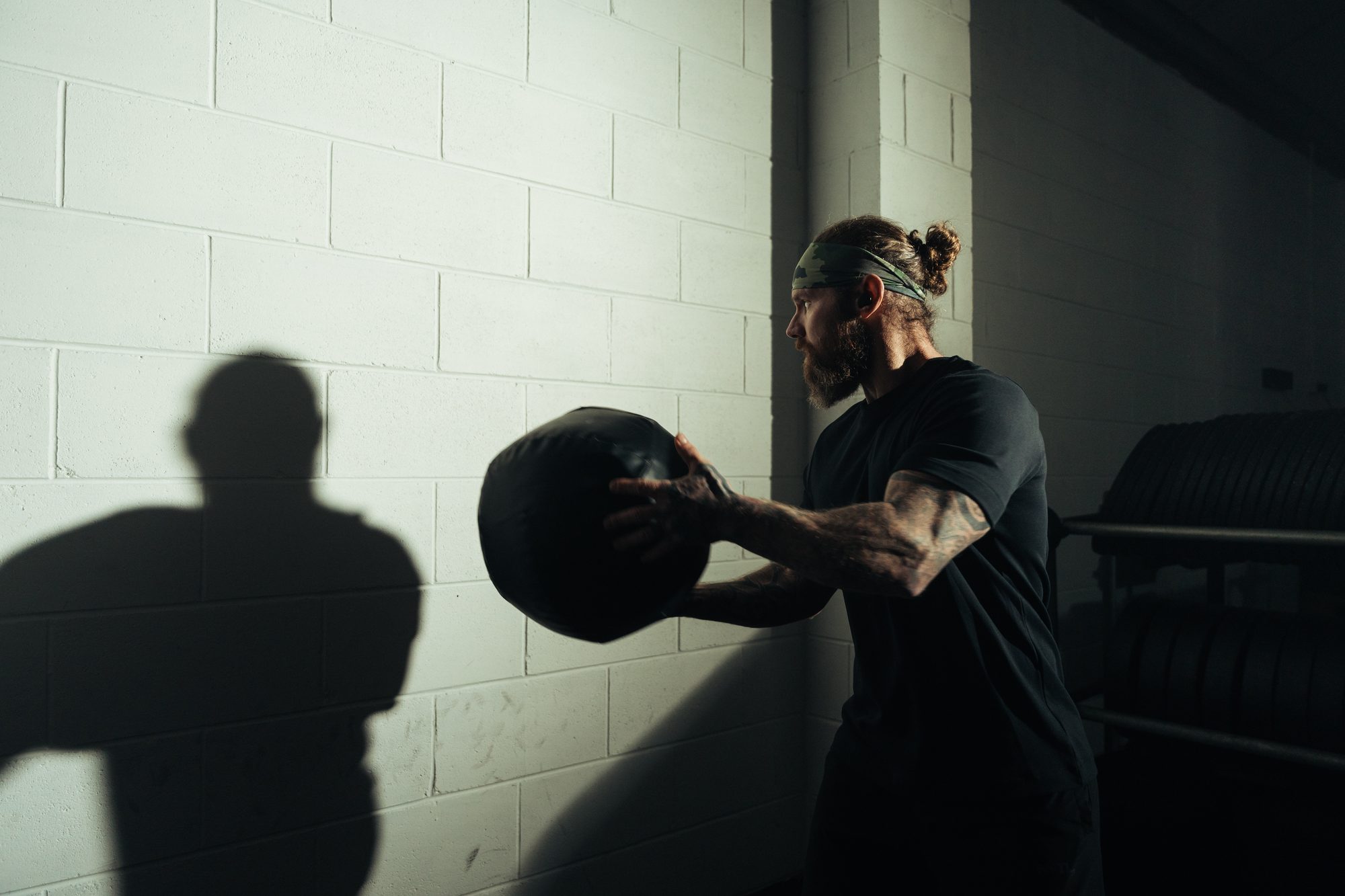 Athlete throwing a medicine ball at a white brick wall during wall ball training for HYROX
