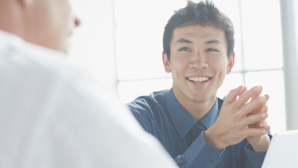 Man in shirt and tie having a conversation with a colleague