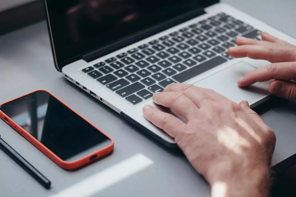 Hands typing on laptop to add certificates to LinkedIn.