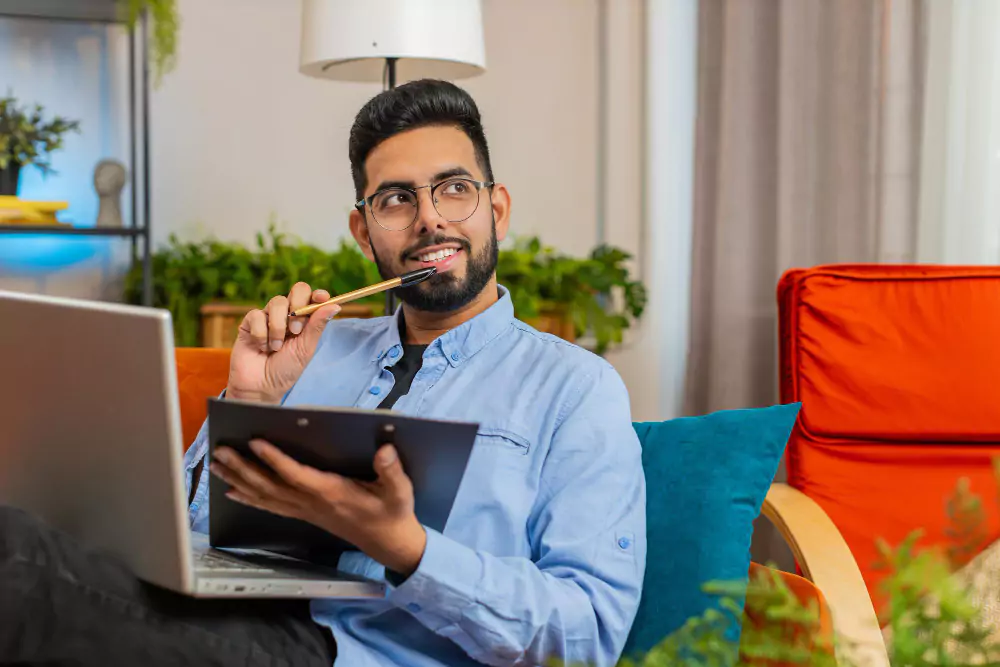 Happy freelancer reading financial documents on laptop