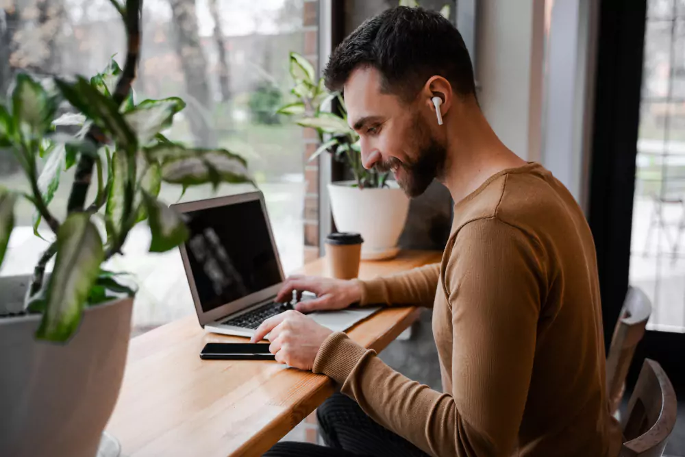 Freelancer wearing wireless headphones working remotely in a café