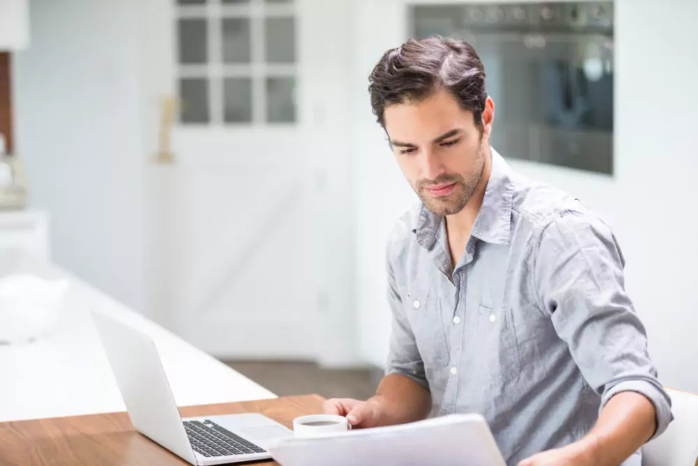 Young man reading his resume while sitting at desk with laptop