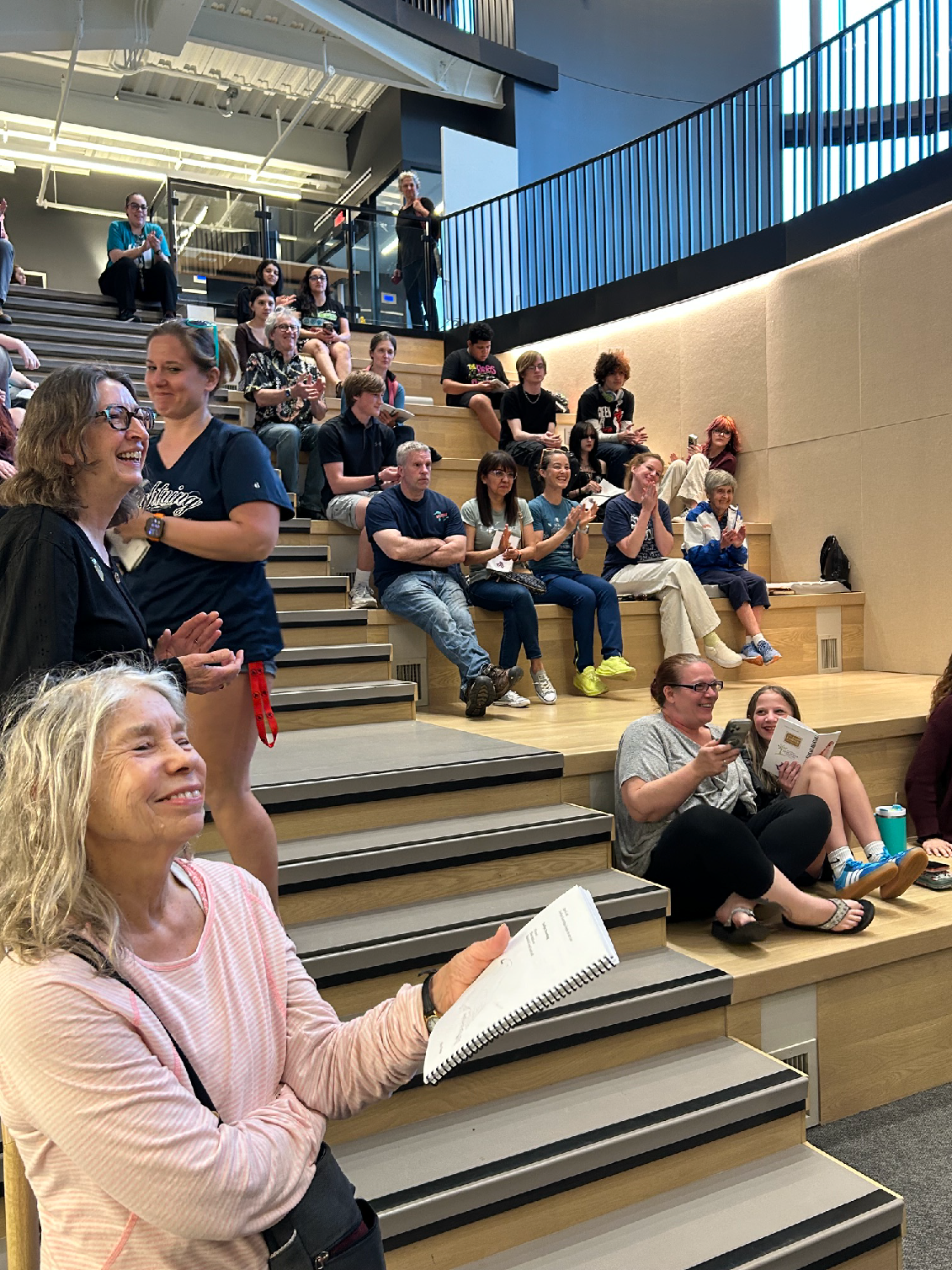 People sit on large auditorium steps at an event.