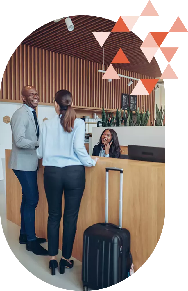 Two people talking to a staff member at a hotel reception desk