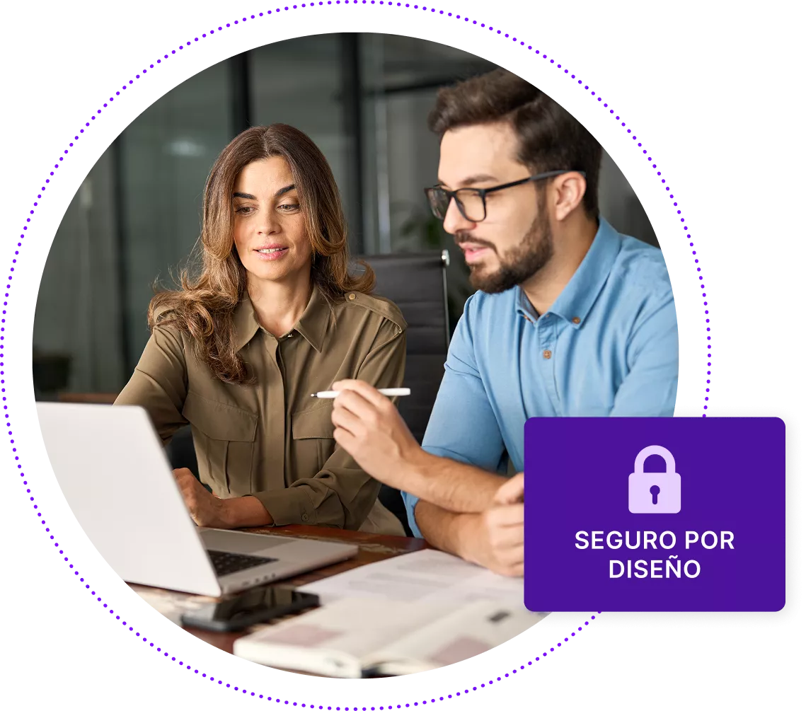 Hombre y mujer sentados en el escritorio mirando el portátil.