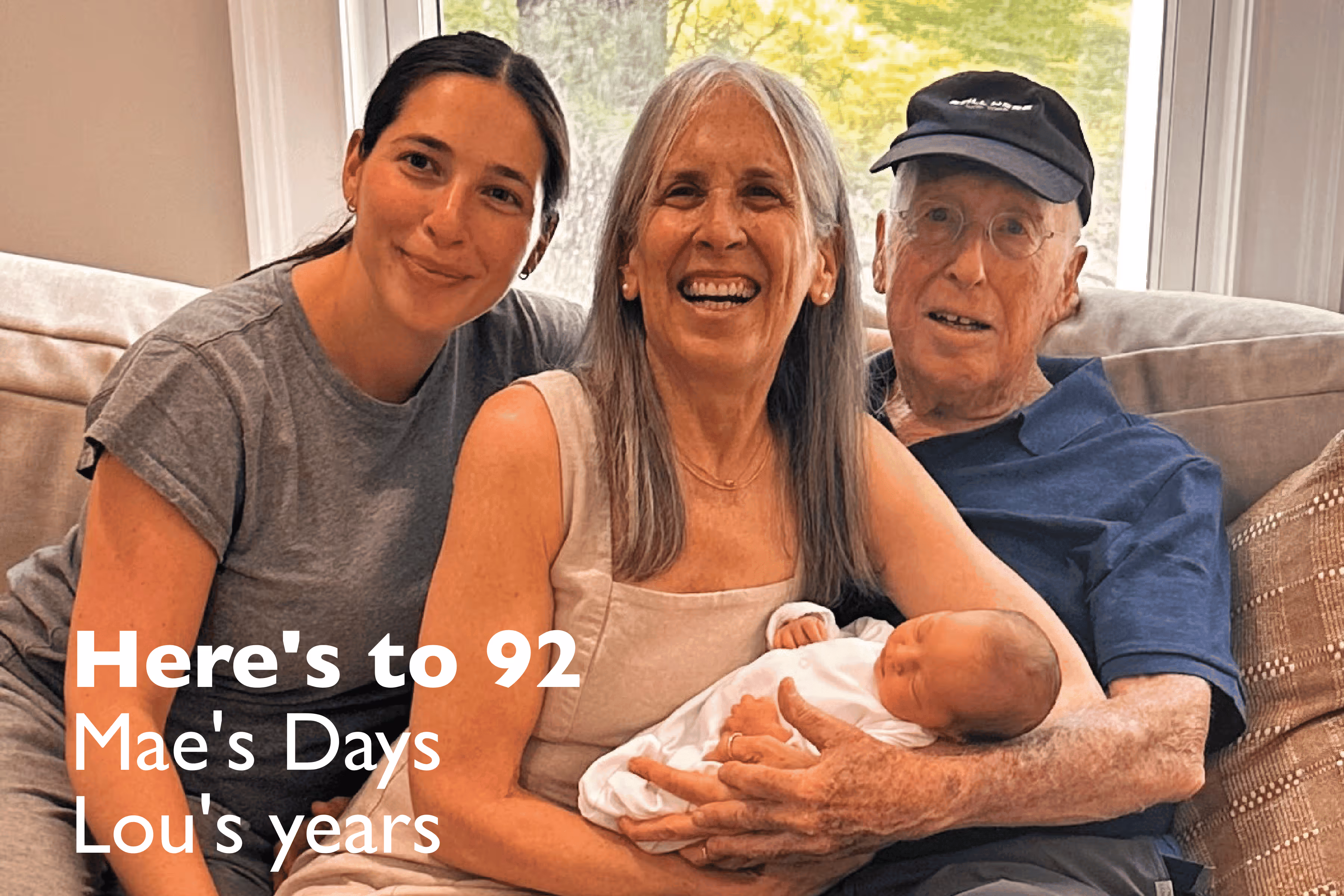 Three generations of a family smiling on a couch, with a woman holding a newborn baby and an elderly man wearing a cap, overlaid text says 'Here's to 92 Mae's Days Lou's years'.
