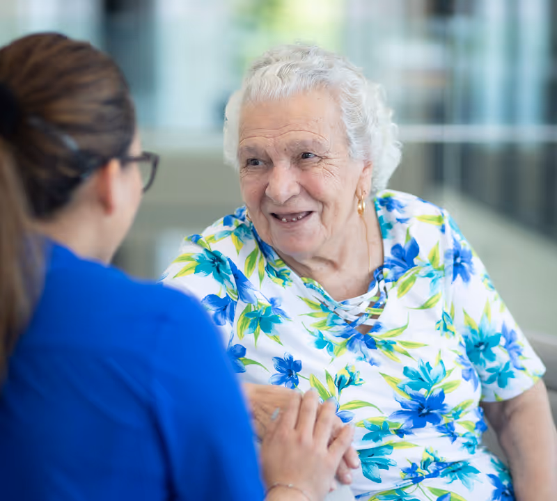 Smiling Italian elderly woman holding hands with a caregiver at Oxa Care