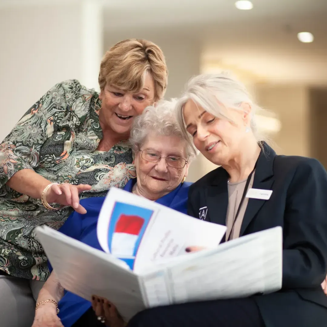 Oxa Care team members looking through a book with a resident.