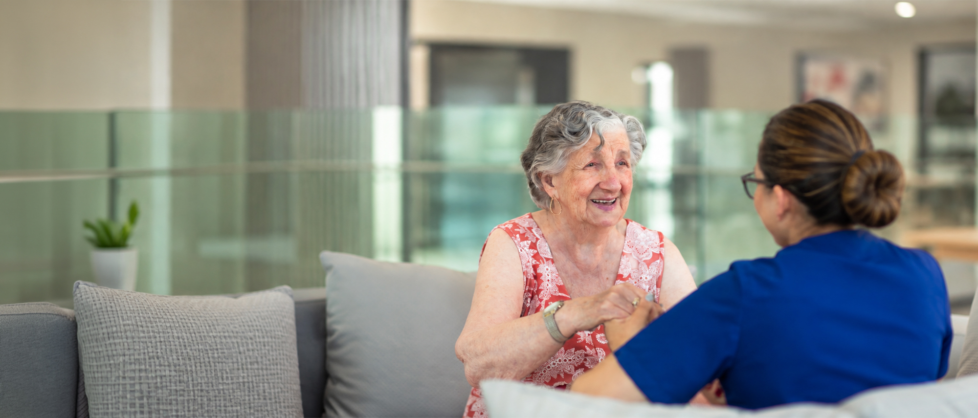 Oxa Care resident smiling while a team member holds her hand.