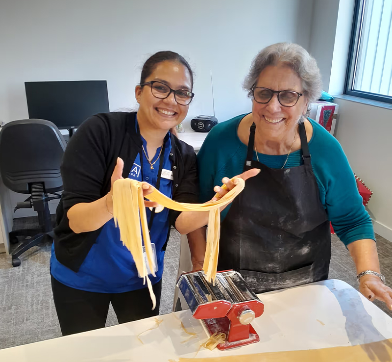 Oxa Care staff member making fresh pasta with a resident.